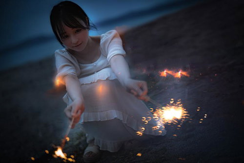 砂浜で手持ち花火を楽しむ女性