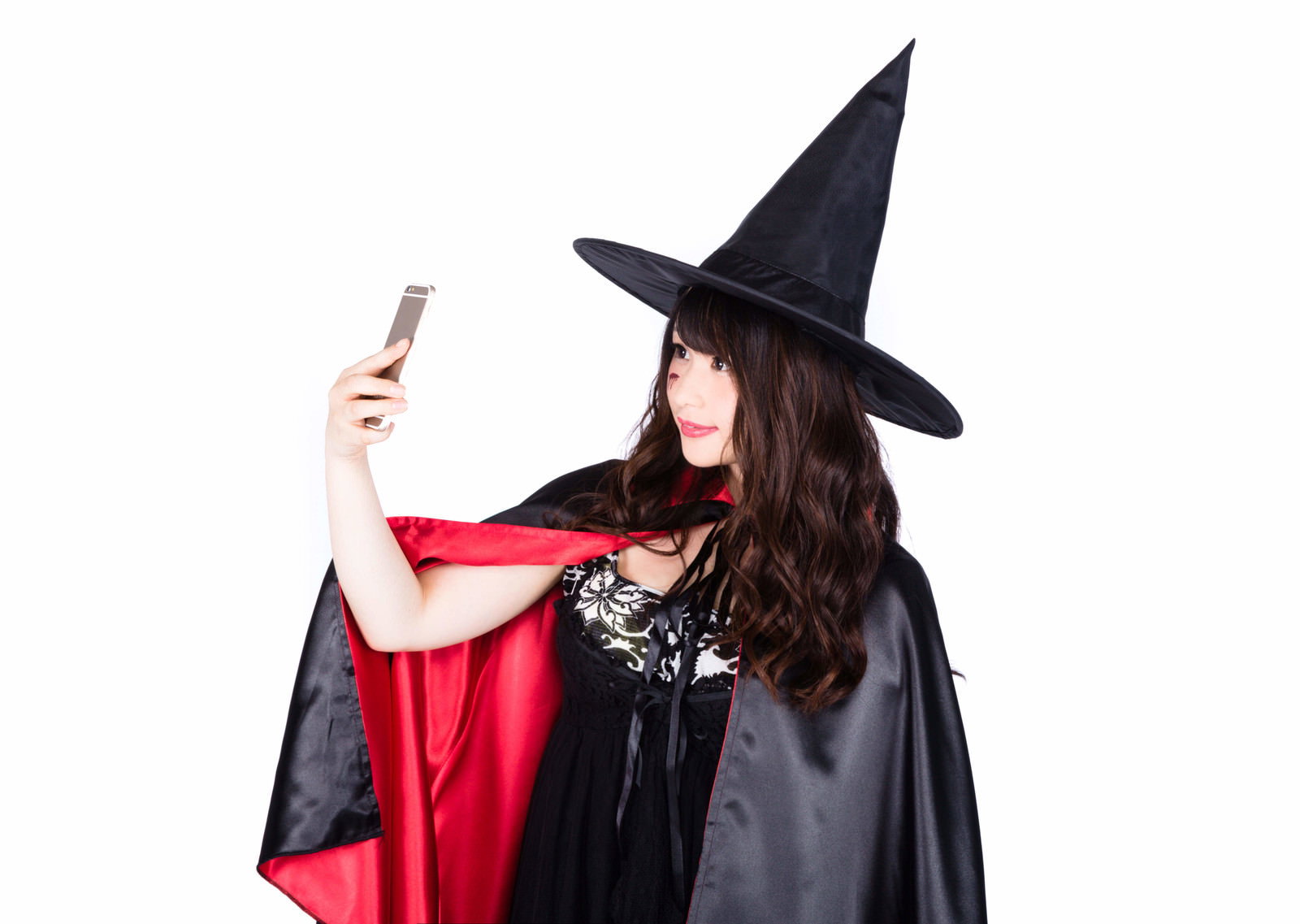 魔女コスプレの女性がスマートフォンで自撮りする［モデル：茜さや］