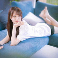 ソファーで横たわってリラックスしながらスマホを見る女性の写真