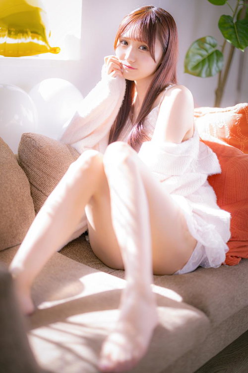 朝の陽だまりの中、ソファーに座る白いシャツの女性