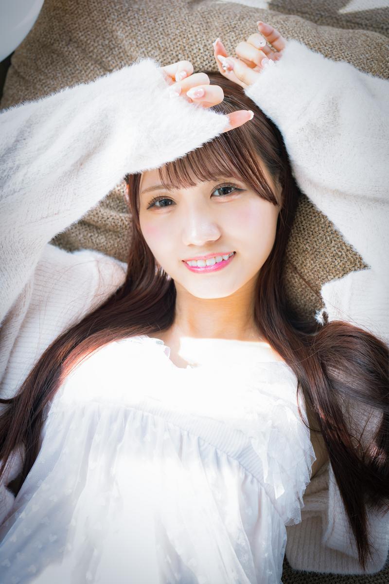 ソファーに横たわり、両手を上げて日差しを遮るファー素材のヘッドバンドを付けた女性［モデル：あき］