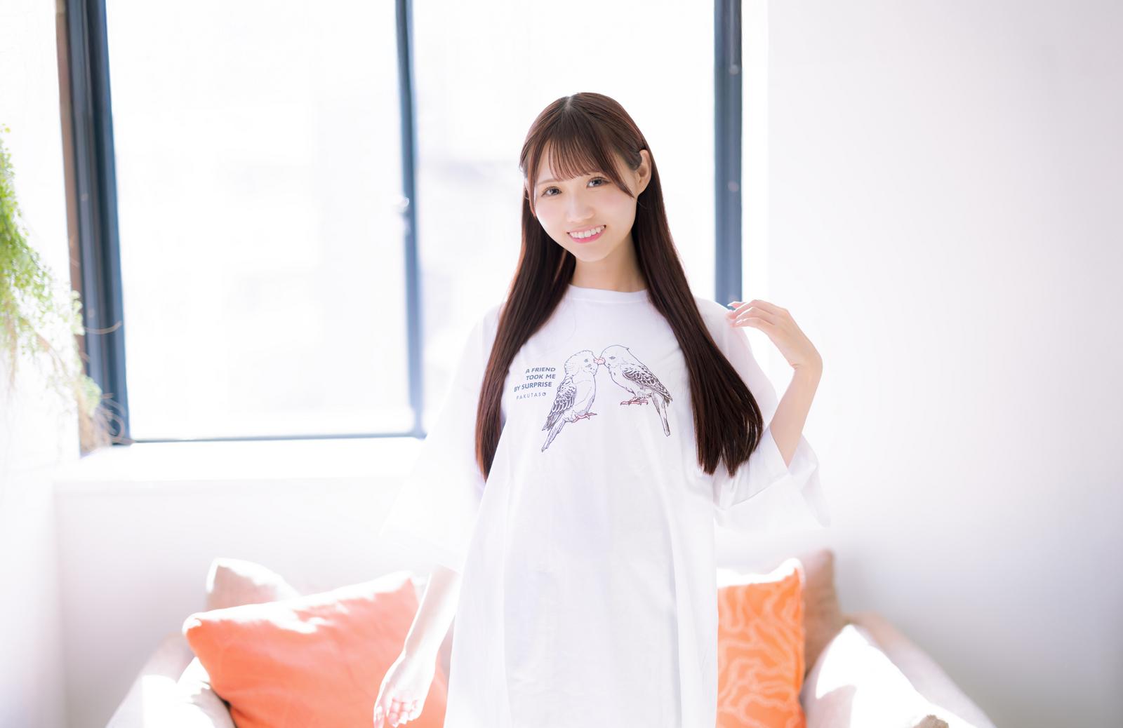 白いTシャツに鳥のイラストプリントをした微笑む長髪の女性［モデル：あき］