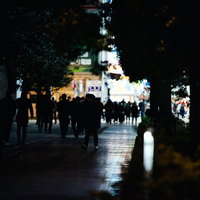 帰宅時間に駅前の歩道へ歩く通行人達の夜間風景の写真
