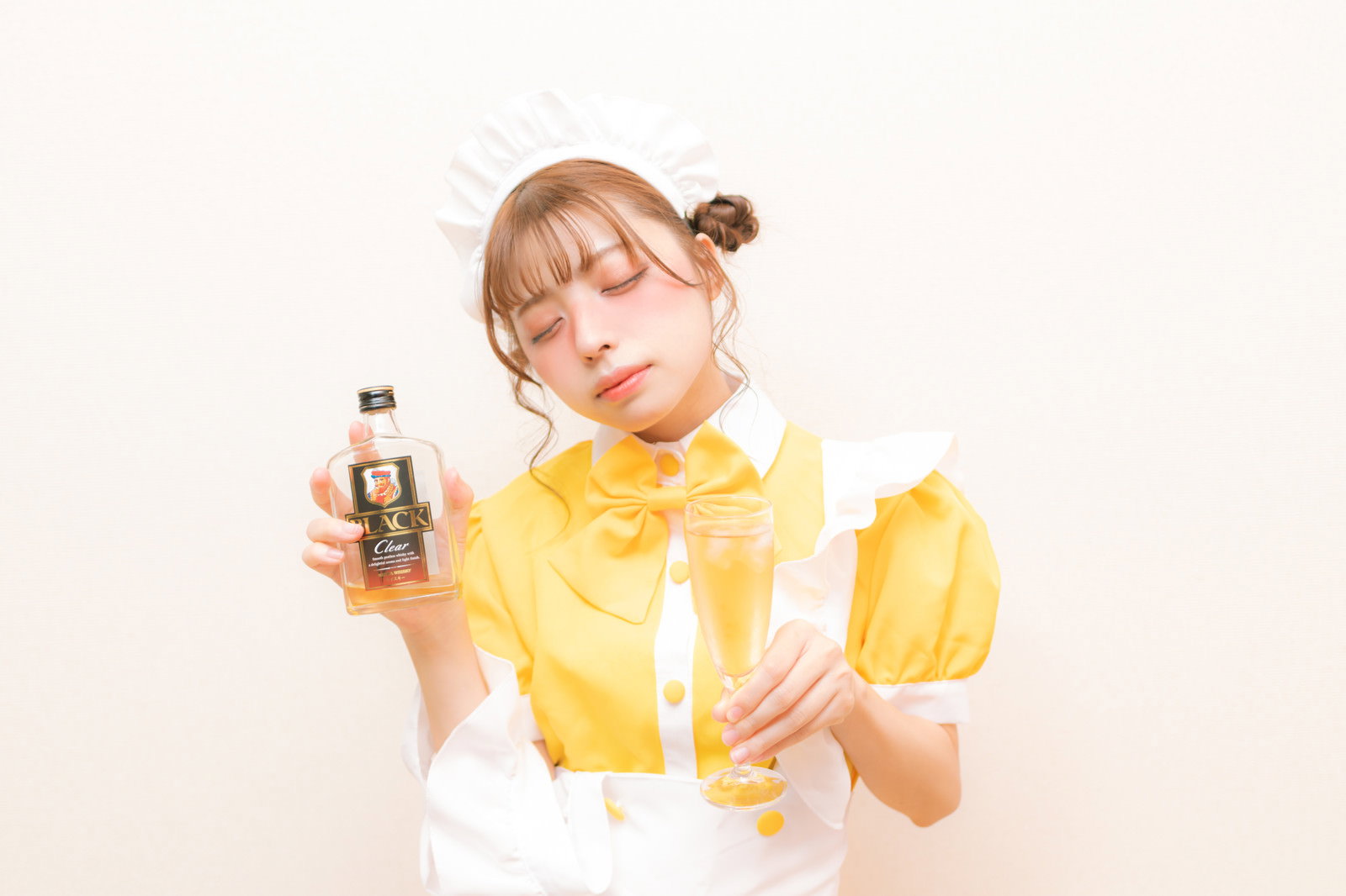 黄色いメイド服の女性がウィスキーとシャンパンを持ち、目を閉じて泥酔している［モデル：高尾実生］