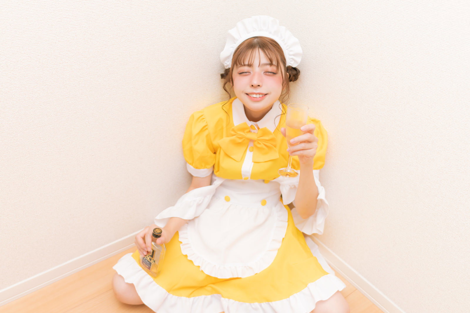 黄色いメイド服を着て泥酔し、グラスを持って笑う女性［モデル：高尾実生］
