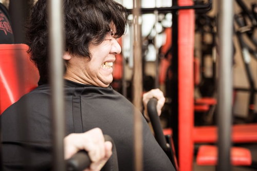 スポーツジムのチェストプレスで大胸筋を鍛えるトレーニー