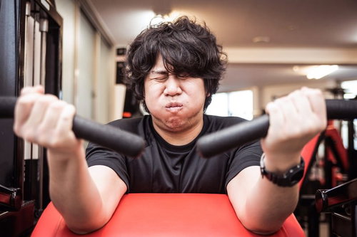 スポーツジムでアームカール中のキス顔でトレーニング