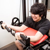 バイセップスカールで二頭筋の収縮に悲鳴を上げる男性の写真