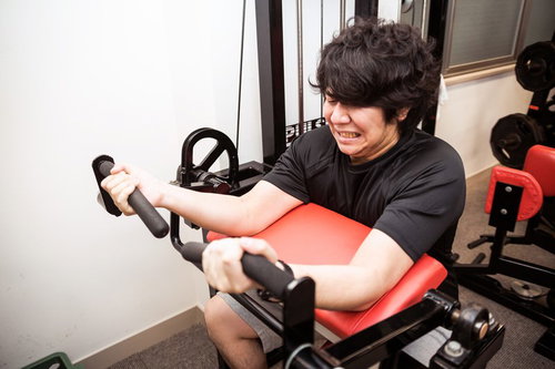 バイセップスカールで二頭筋の収縮に悲鳴を上げる男性