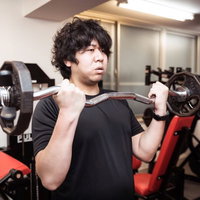 EZバーを使ったバーベルカールでトレーニングする男性の写真