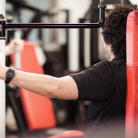 鏡を見ながらトレーニング機器でフォームの確認をする男性の写真