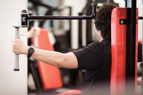 鏡を見ながらトレーニング機器でフォームの確認をする男性