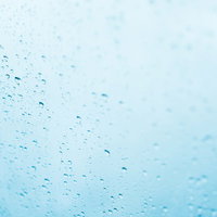 窓ガラスに付着した雨粒としずく。梅雨時期の雨の日の写真