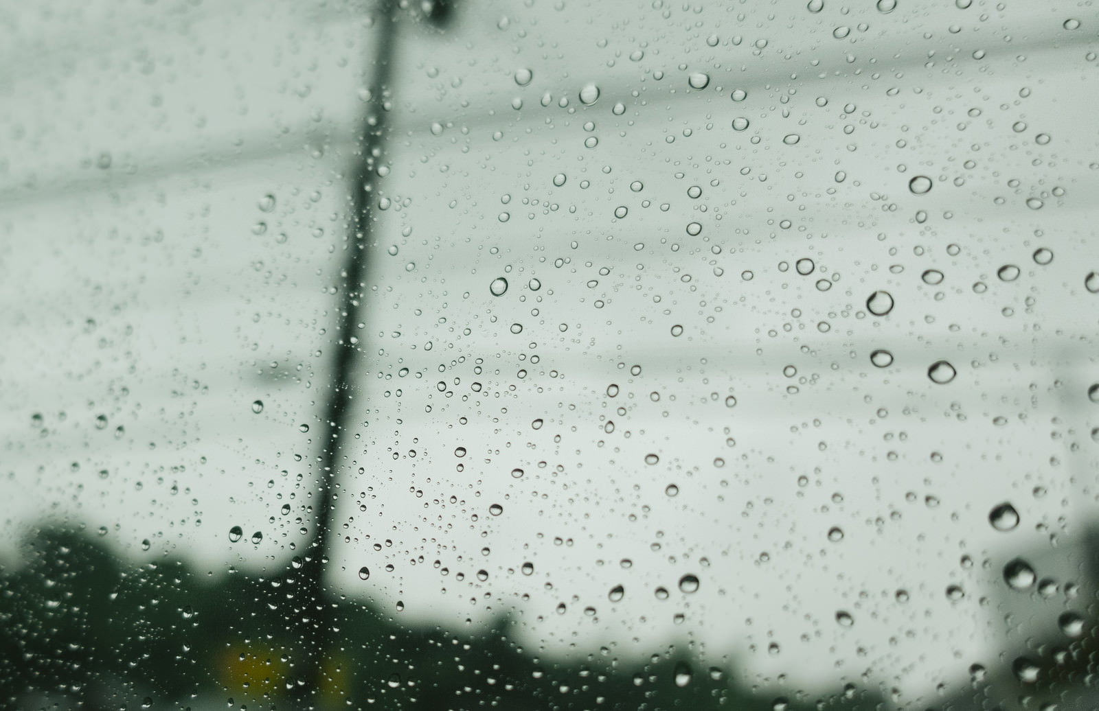 雨空を背景に窓ガラスに付いた大小の水滴