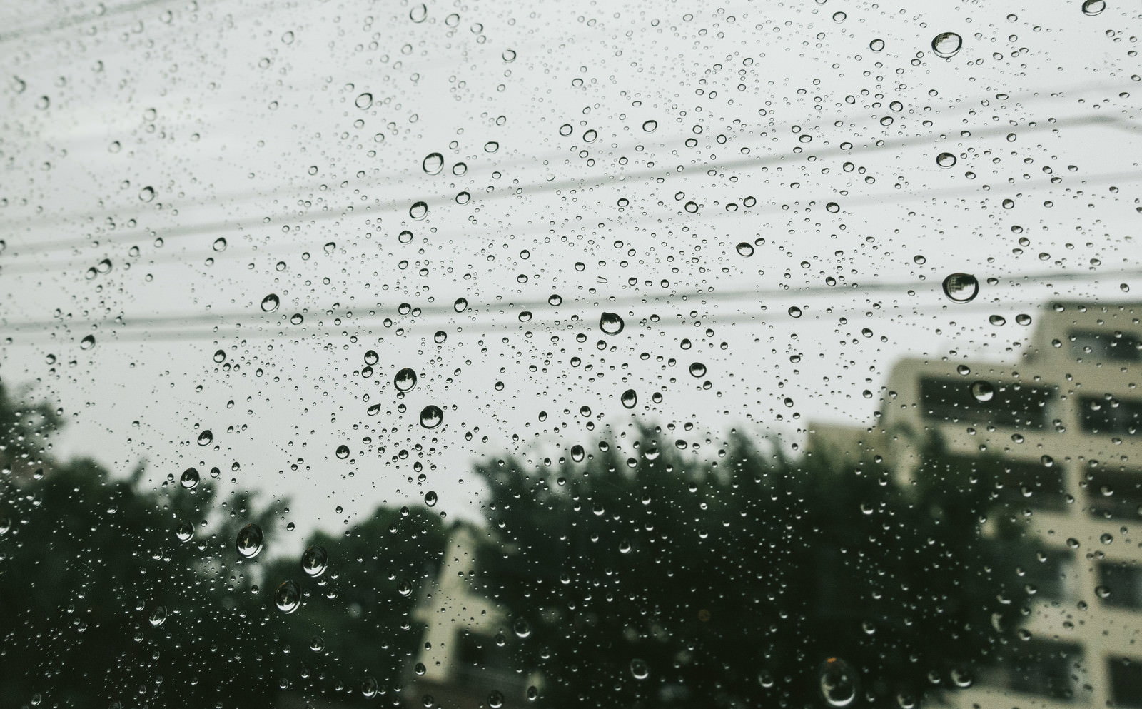 窓ガラスに付いた大小の雨粒と向こう側にぼんやり見える風景