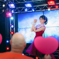 ステージ上で踊るアイドルを応援するデブハート掲げるファンの写真