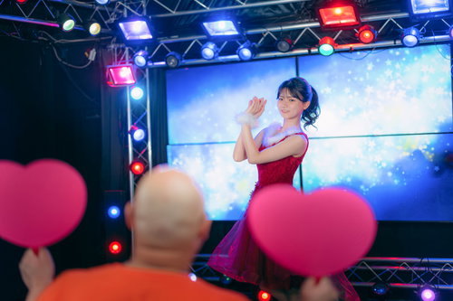 ステージ上で踊るアイドルを応援するデブハート掲げるファン