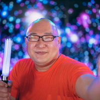 笑顔でペンライトを振る眼鏡姿の男性、ライブ応援の写真