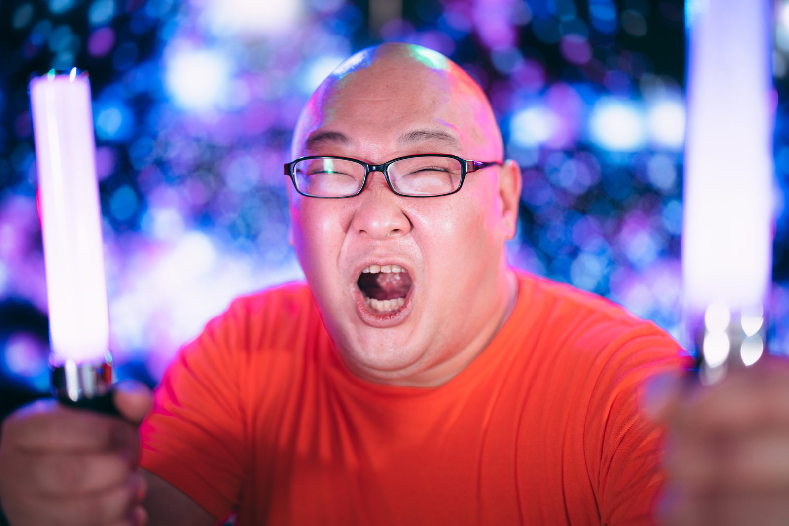 ペンライトを持ち声援を送る赤いシャツの男性ファン［モデル：あまやん］