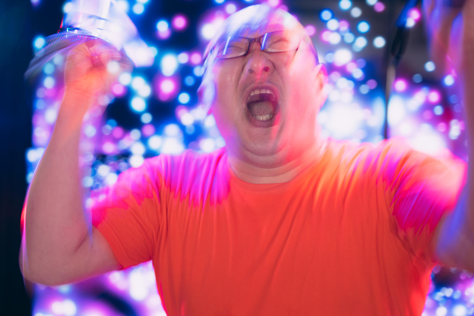 ペンライトを掲げて熱狂的に応援する男性、目を閉じて口を開け声援を送る［モデル：あまやん］