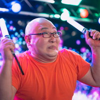 推しのために無我夢中でペンライトを振る男性、ネオンライトに照らされたステージの写真