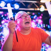 ペンライトを掲げて推し活に熱狂する眼鏡の男性ファンの写真