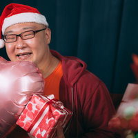 クリスマスプレゼントに笑顔が溢れるメガネの男性の写真