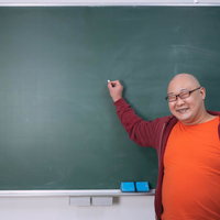 満面の笑みで黒板の前に立つ授業をするアンバサダーの写真
