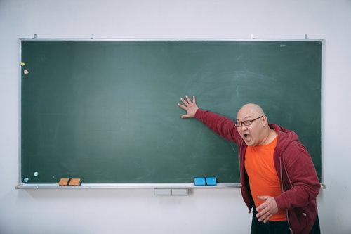 黒板を指して大声で叫ぶ熱血教師が授業で激怒する場面