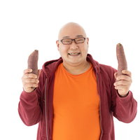 左手に焼き芋、右手にも焼き芋で笑顔の男性の写真