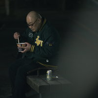 公園のベンチで夜中にストゼロとカップ麺を食べる男性の写真