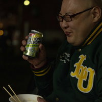 夜の街でストゼロを飲みながらカップ麺を食べる男性の写真