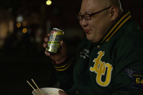 夜の街でストゼロを飲みながらカップ麺を食べる男性