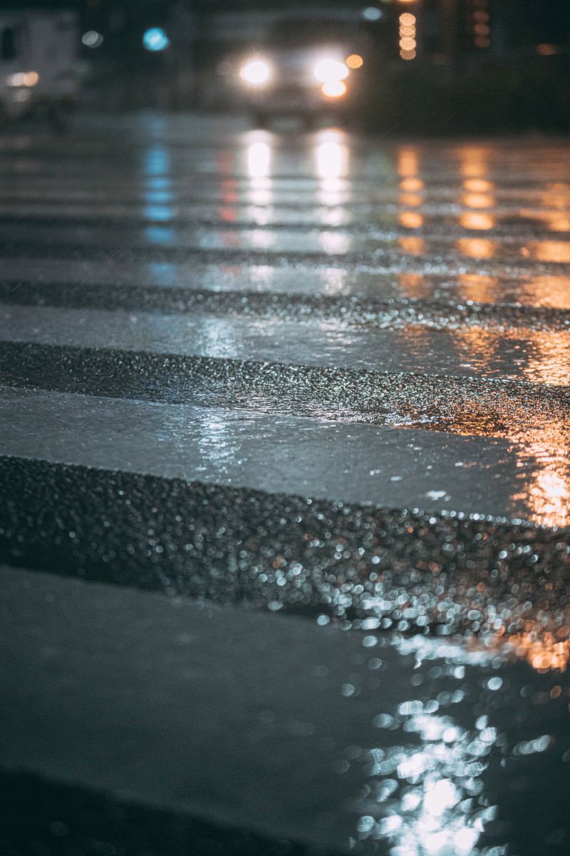 雨で濡れた夜の横断歩道、アスファルトに街灯の光が反射している様子