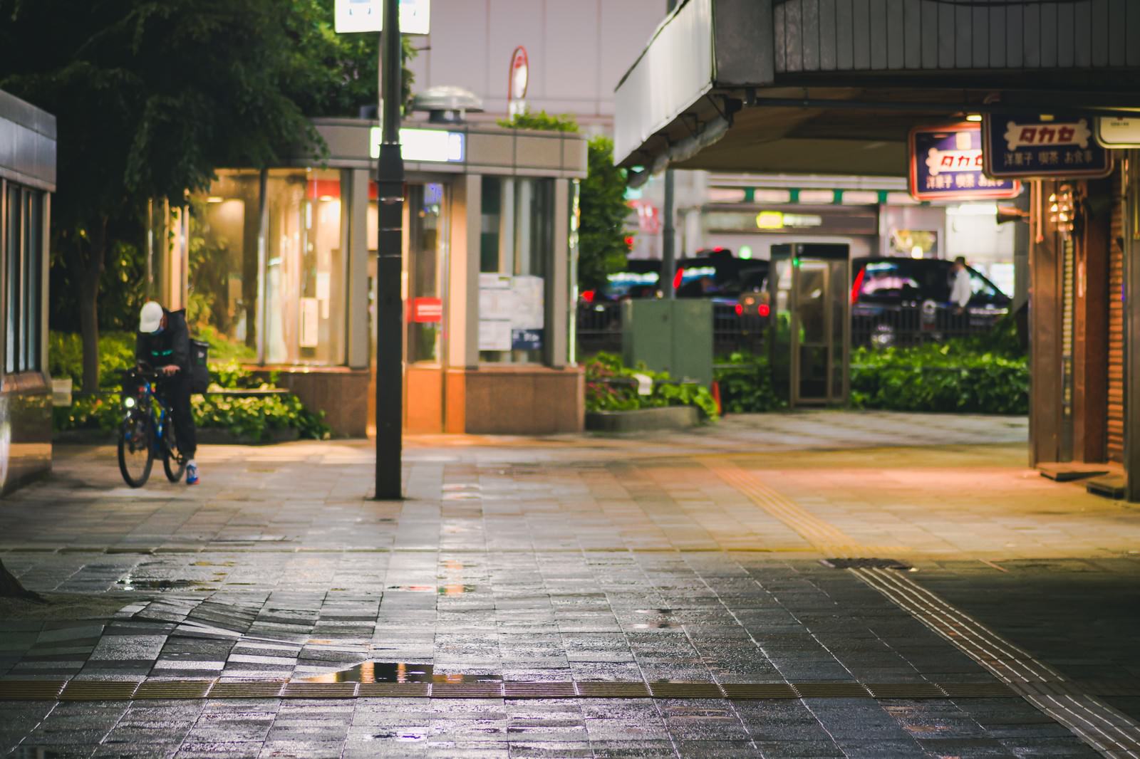 雨に濡れて光る石畳の夜の歩道と両側に並ぶ温かい光の店舗