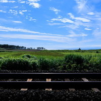 一本の線路と広がる青空の草原の写真