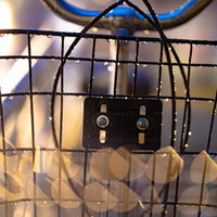 夜の雨に濡れた自転車の前バスケットと街灯の光が映る水滴の写真