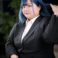 ビジネススーツを着た青髪の女性が髪をかき上げるの写真
