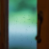 ガラス窓についた雨粒と水滴 室内からの雨の日の風景の写真