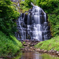 川に映り込む鳥海檜山滝と新緑の渓谷、柱状節理の岩肌の写真