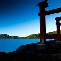 田沢湖の朝焼けに浮かぶ御座石神社の鳥居と薄明の情景の写真