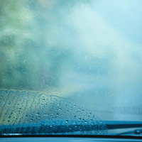 雨天時の車のフロントガラスに付着した雨滴とワイパー跡の写真