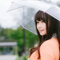 雨の日に透明な傘をさす笑顔の長髪女性のポートレートの写真