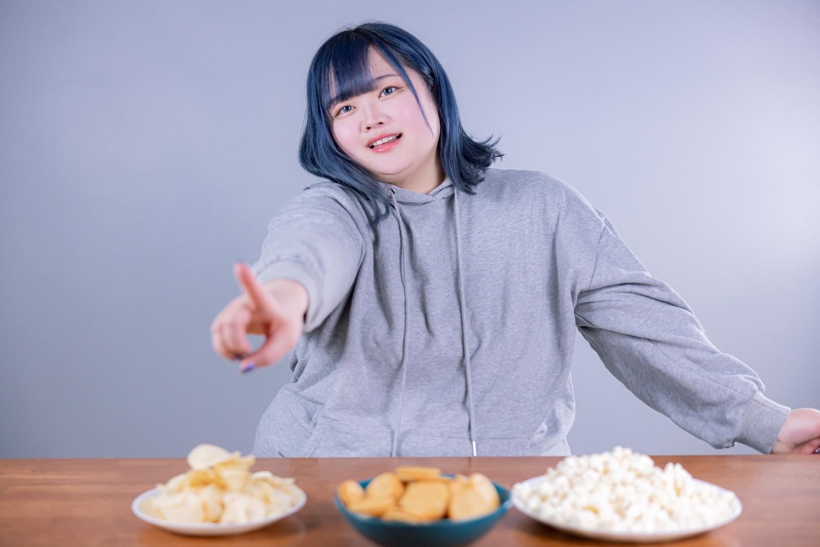 テーブルのお菓子を指さしておねだりする女性［モデル：あねちゃん］