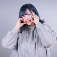 笑顔を見せながら両手で頬にハートを作るぽっちゃり女子の写真
