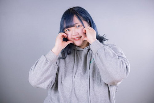 笑顔を見せながら両手で頬にハートを作るぽっちゃり女子