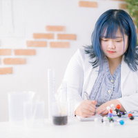 白衣を着た青髪の女性が電子部品で実験作業をするの写真