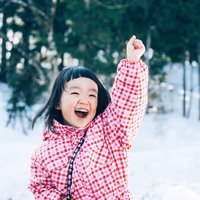 雪だるまつくるよー！ピンクチェック姿ではしゃぐ子どもの写真