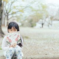 公園で洋書を読む女の子の読書風景の写真