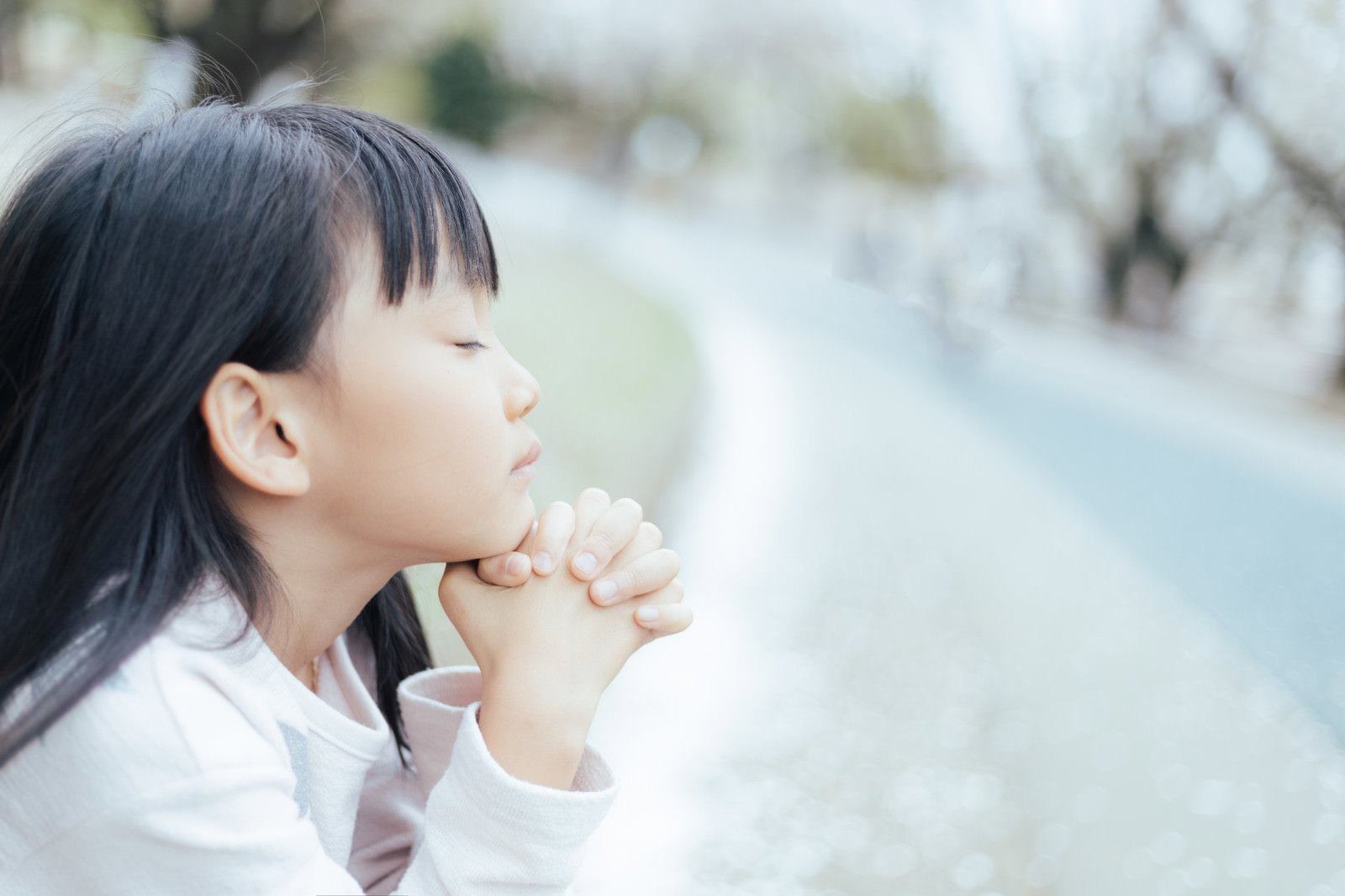 両手を合わせて祈りを捧げる白い服の女の子［モデル：あんじゅ］